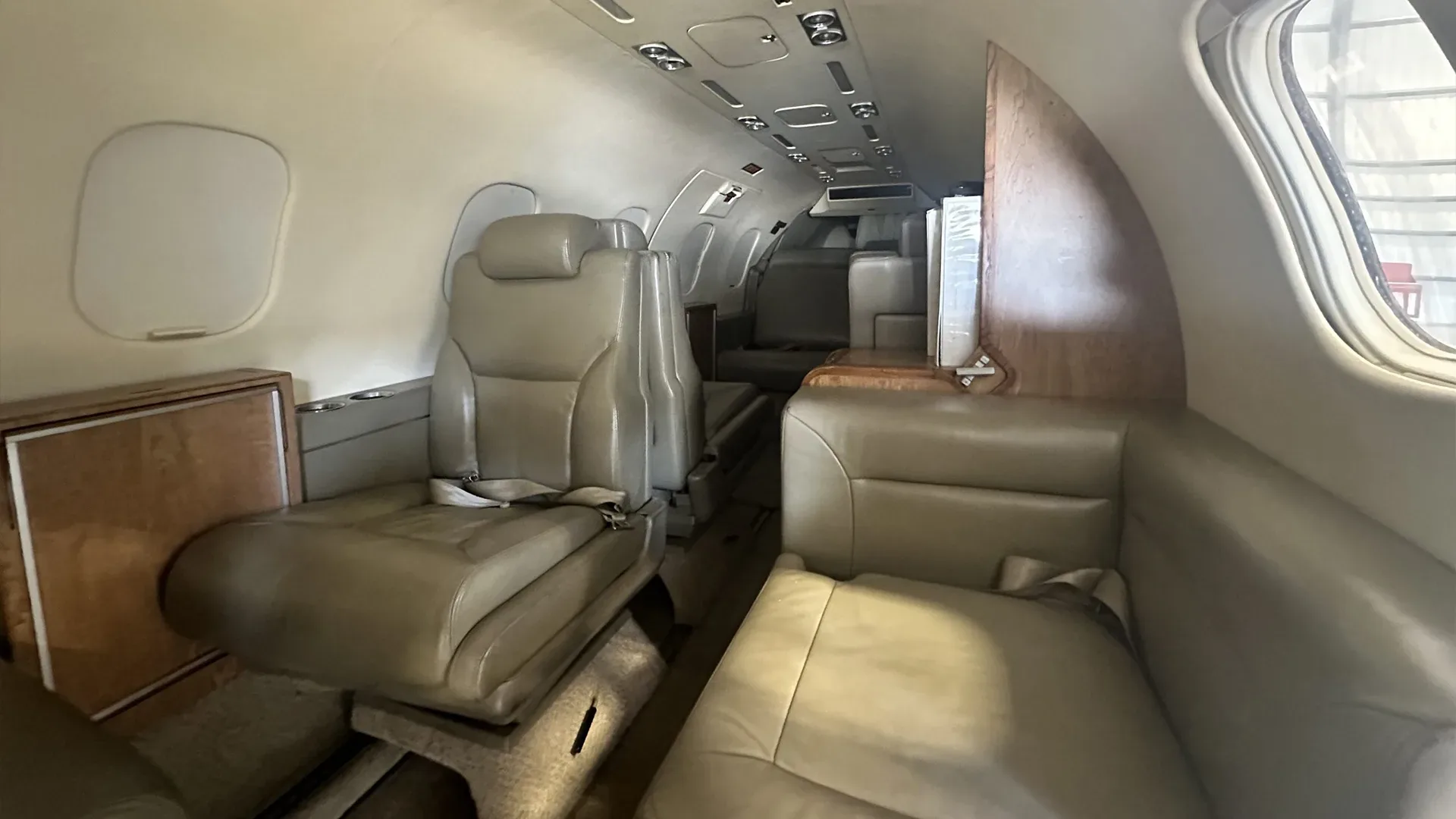The interior of a Learjet 25D aircraft features leather seats and wood trim.
