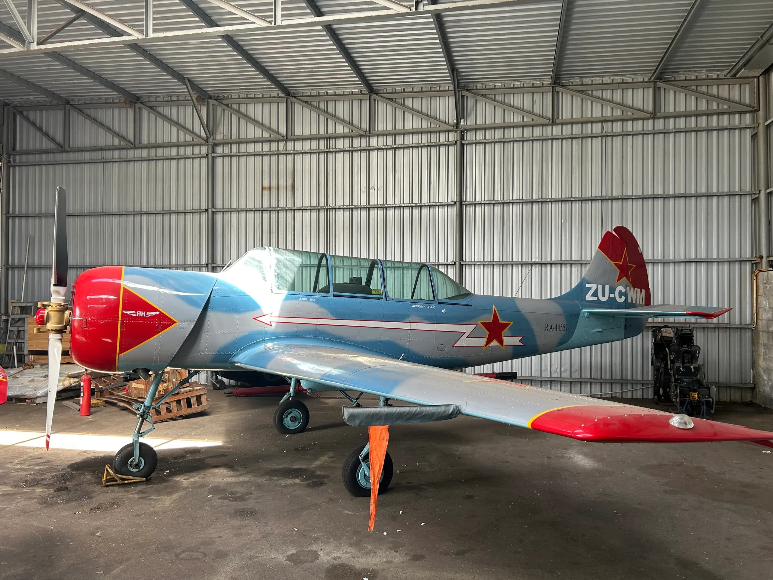 Yak-52 trainer aircraft in a hangar, side view.