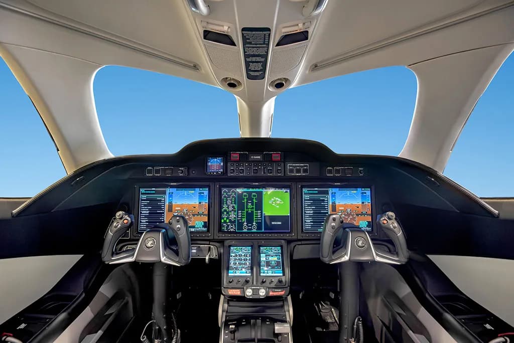 The modern glass cockpit of a HondaJet HA-420, featuring multiple digital displays and control yokes.