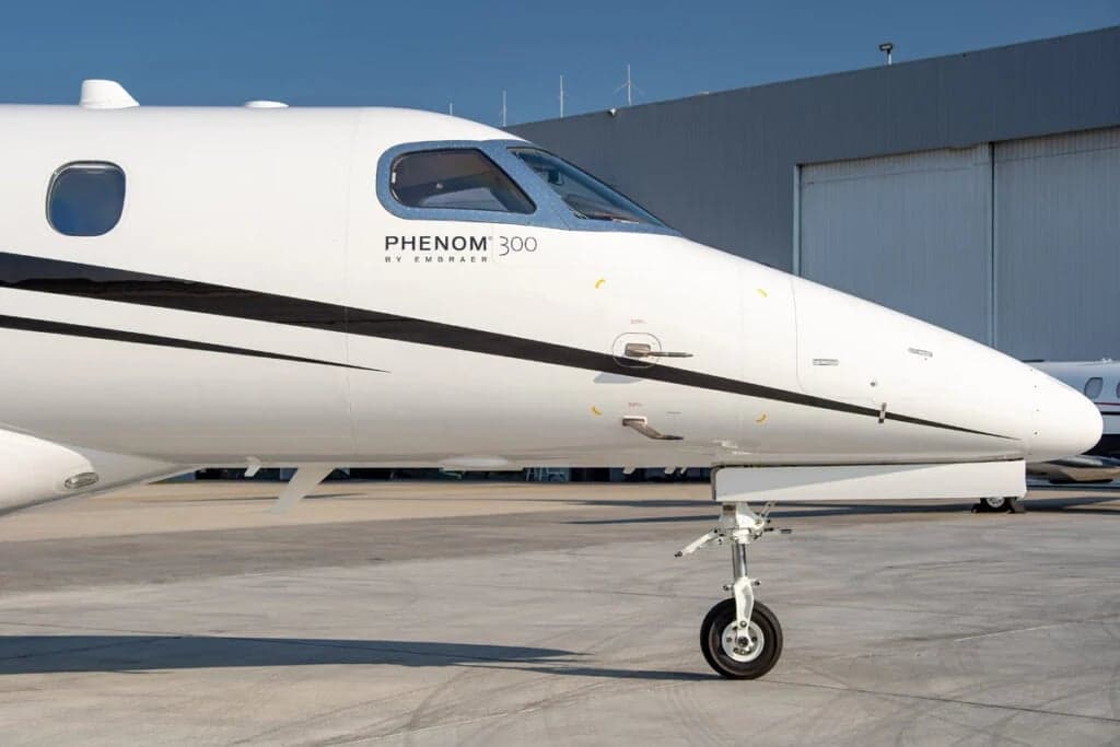 Close-up of the nose of a Phenom 300 aircraft, showing the landing gear.