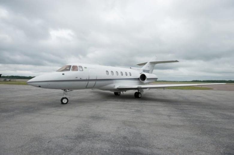 A white jet with blue stripes sits on the tarmac.