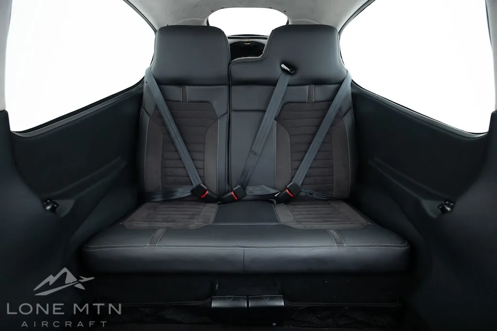 The black leather rear seats of a Cirrus SR22 aircraft cabin with seatbelts.