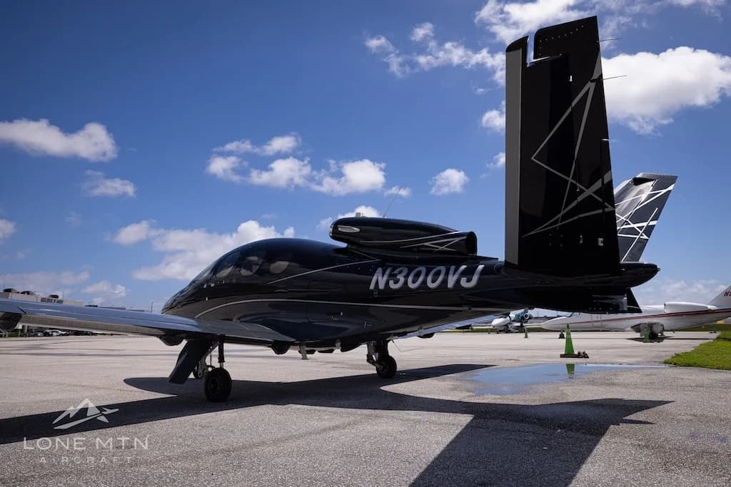 A black Cirrus Vision Jet (N300VJ) with silver accents parked on an airport tarmac, viewed from the rear-right.