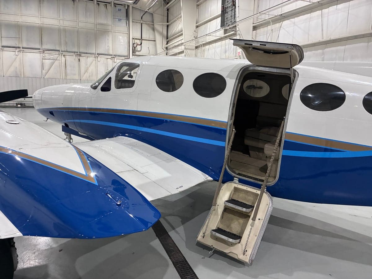 The open door and steps of a white and blue Cessna aircraft are visible.