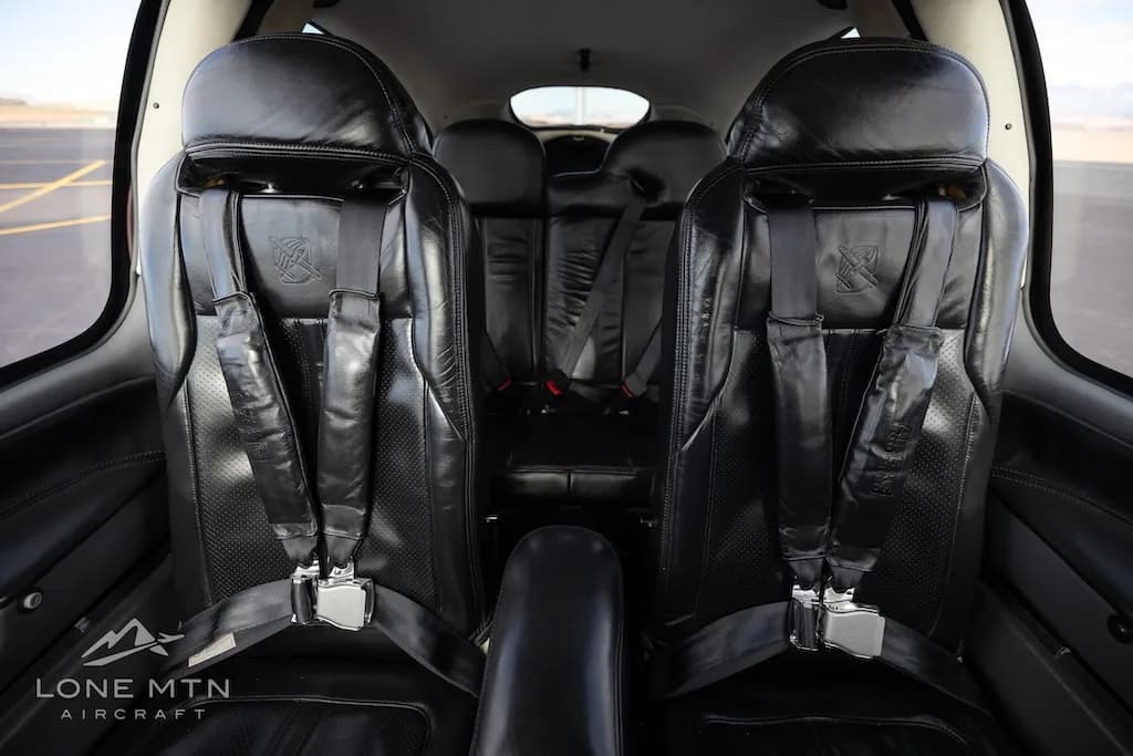 The black leather front seats of a Cirrus SR22 aircraft cabin, showing seatbelts and headrests.