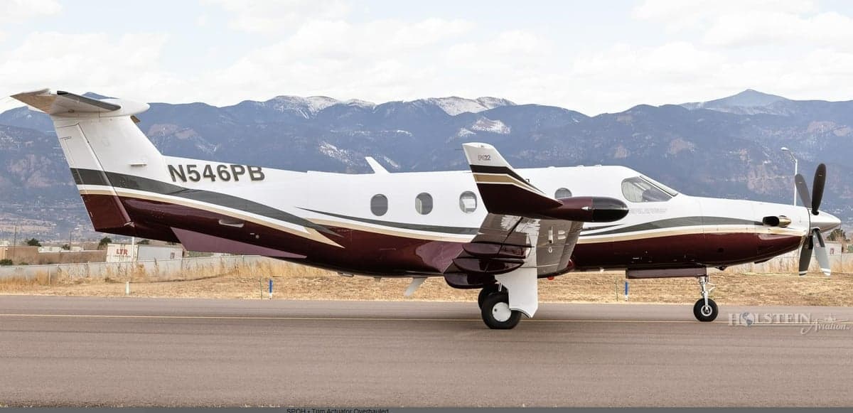 Pilatus PC-12 aircraft N546PB on the runway, side view with mountains in the background.