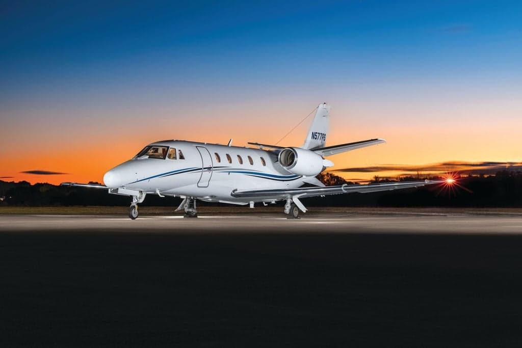 A Cessna Citation CJ3+ aircraft with registration N577PS parked on the tarmac at sunset.