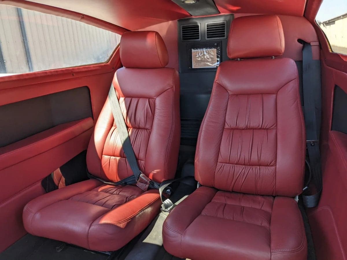 Interior view of the N7779X aircraft cabin with red leather seats.