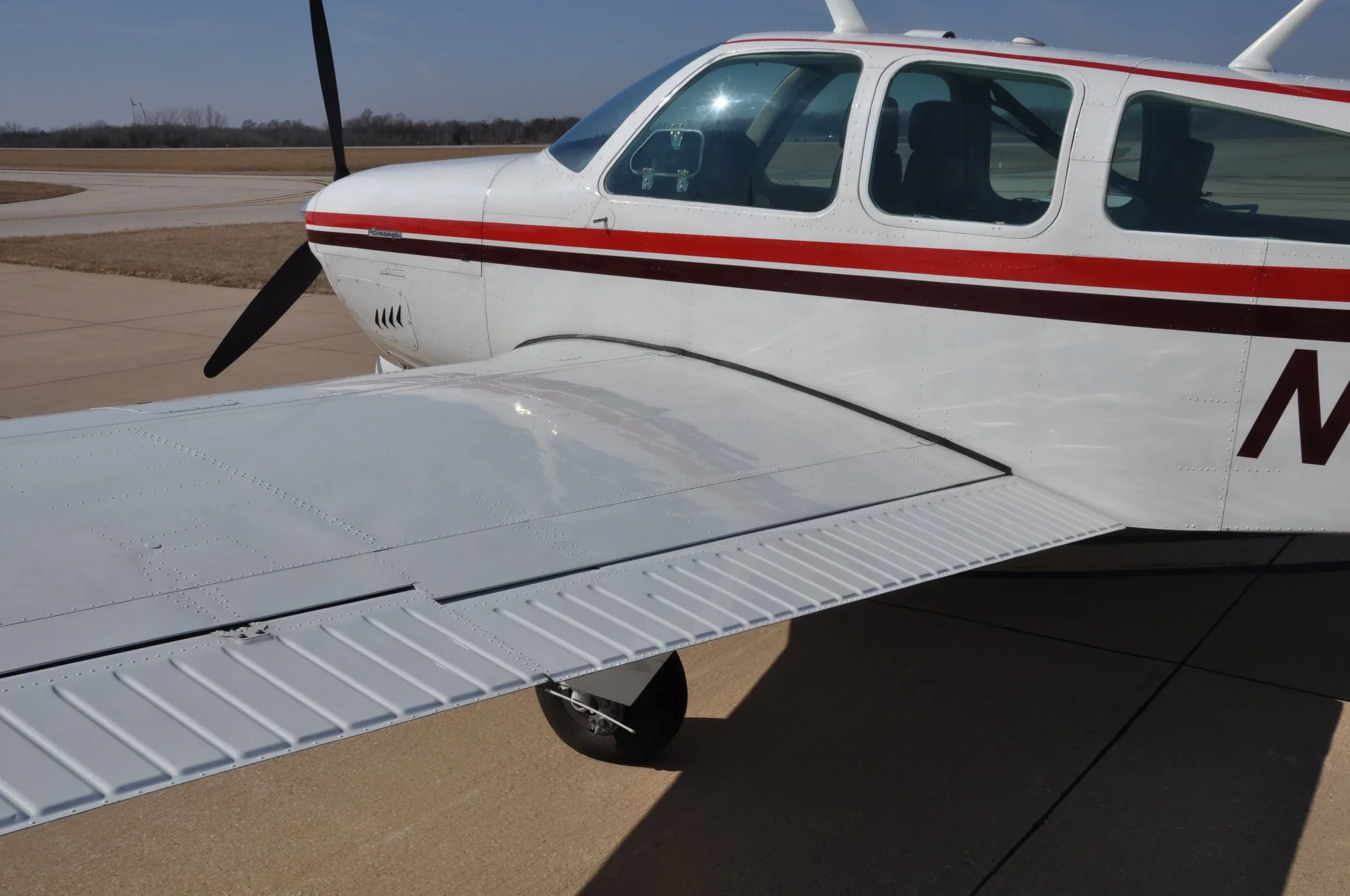 A close-up view of the aircraft's right wing and fuselage, highlighting the rivets and white paint.