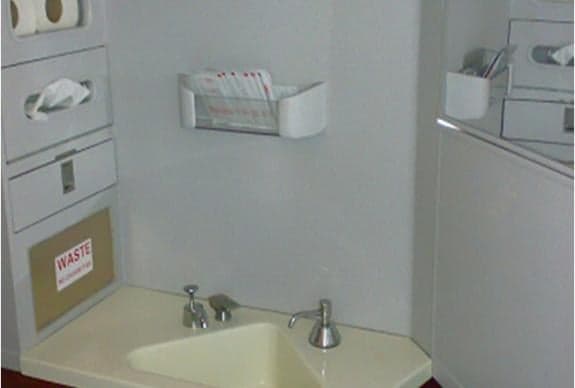 Interior view of aircraft lavatory with sink and storage.