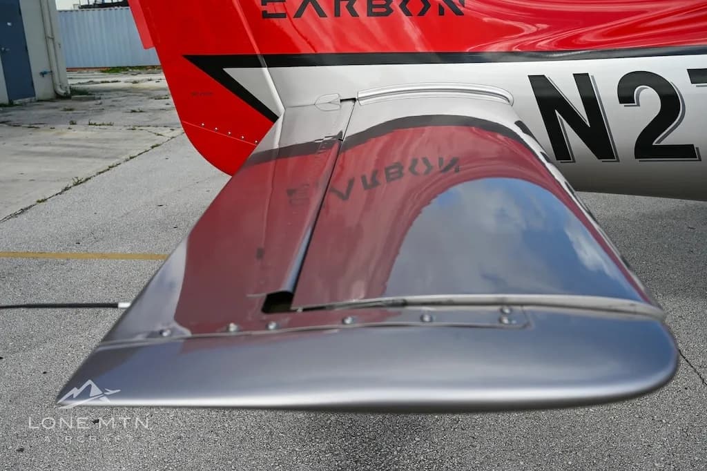 A close-up view of the silver wing and horizontal stabilizer of a Cirrus SR22 aircraft, showing reflections of the tail.