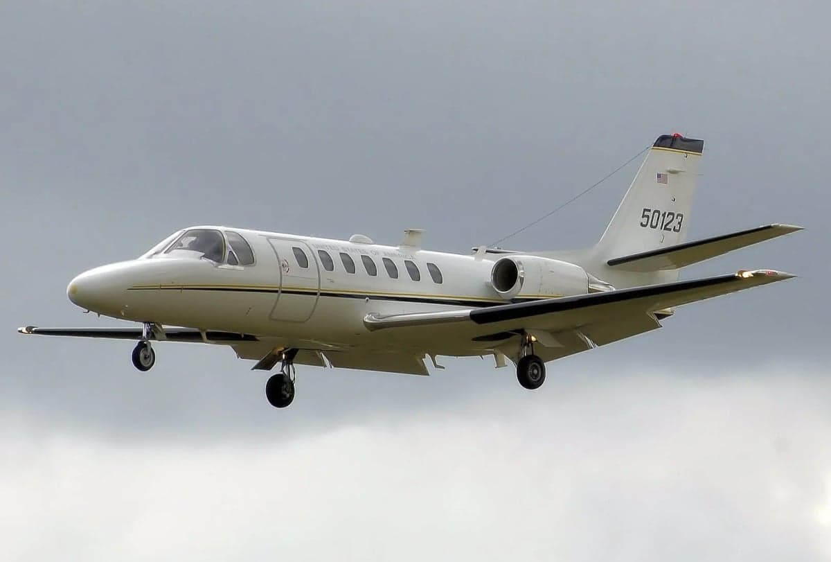 A white Cessna Citation jet with tail number 50123 is shown in flight against a cloudy sky.
