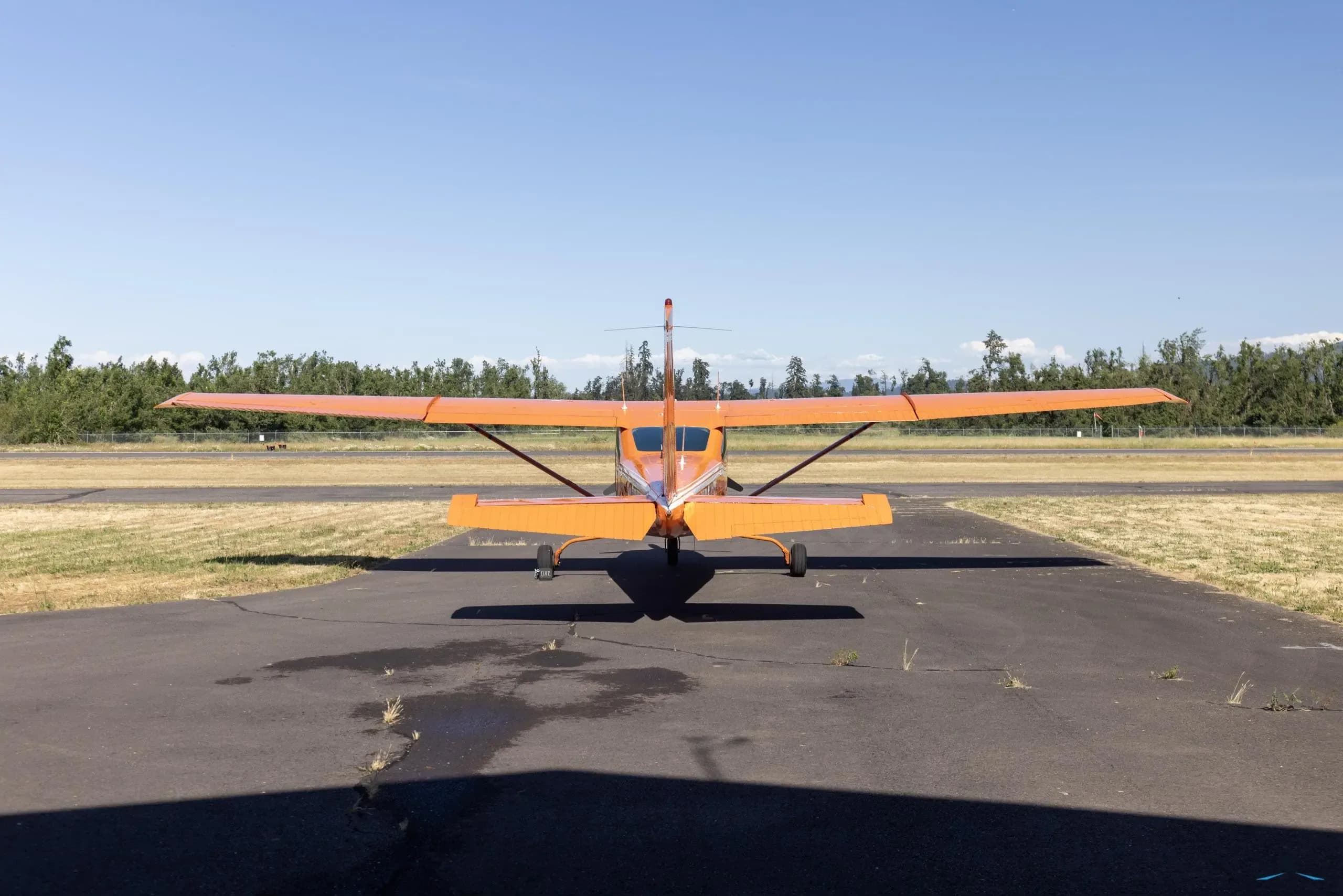 Rear view of the orange and white Cessna 182 Skylane RG parked on the tarmac.