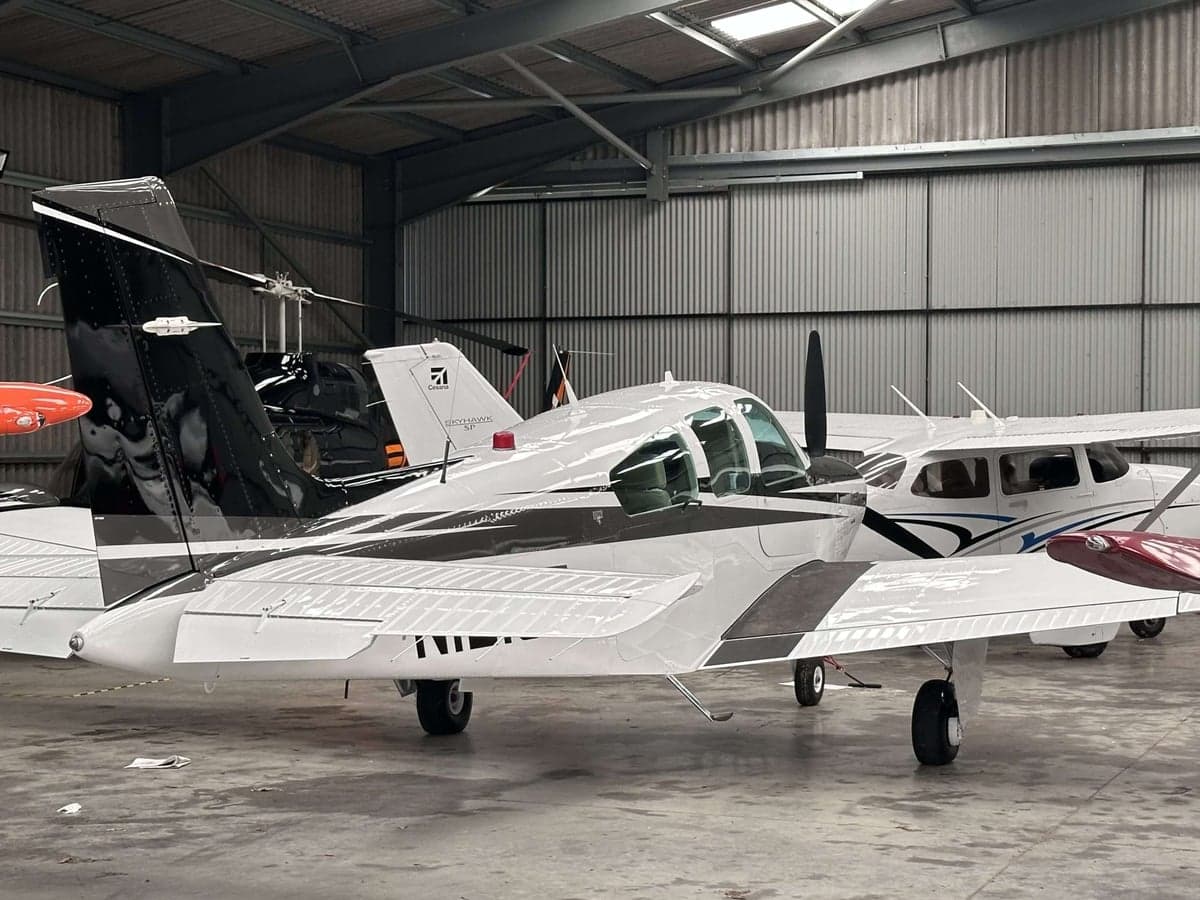 A Beechcraft Bonanza parked inside a hangar with other aircraft.