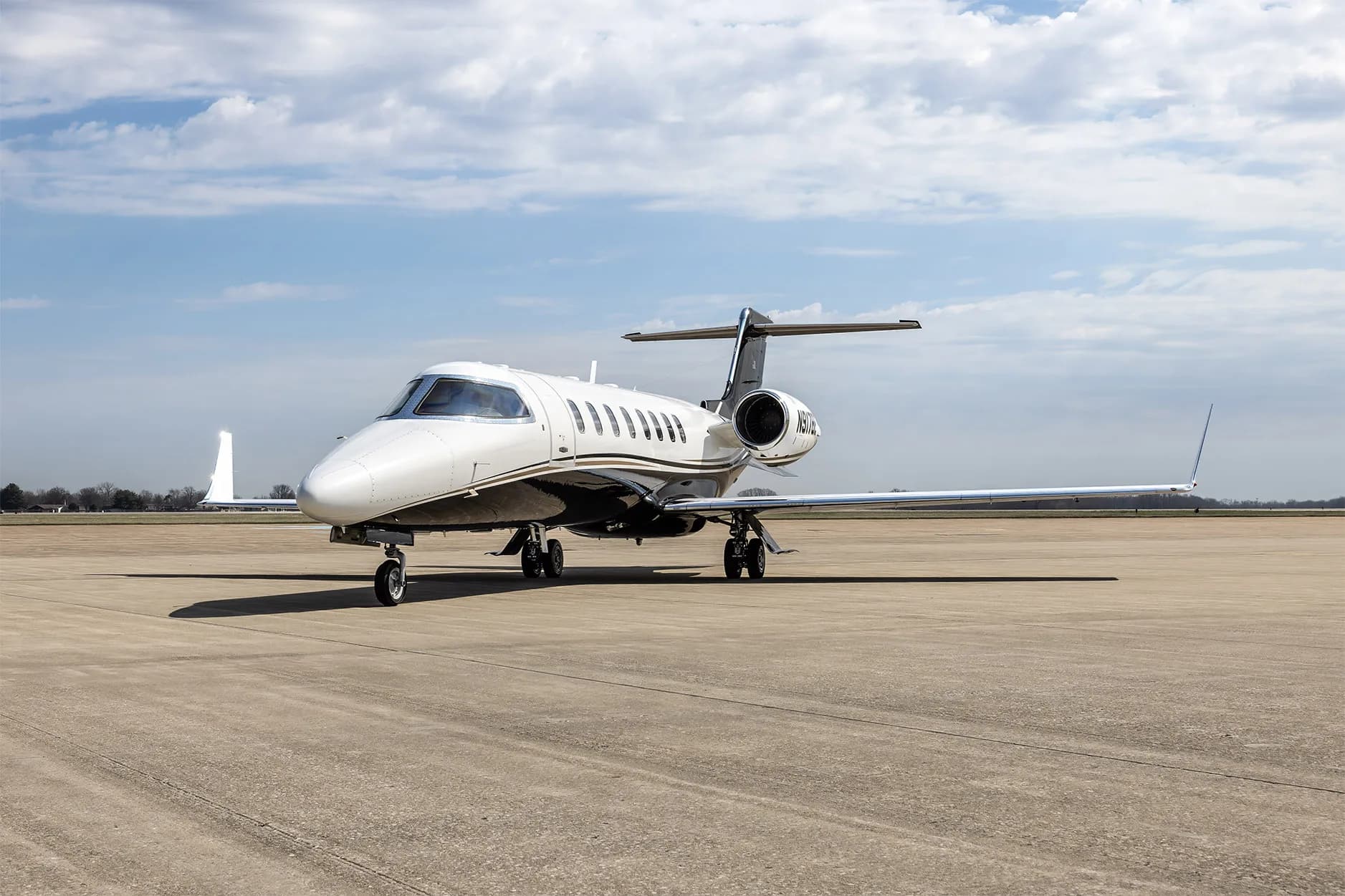 A Learjet 60 business jet with a white and black paint scheme parked on an airfield, viewed from the front-right.