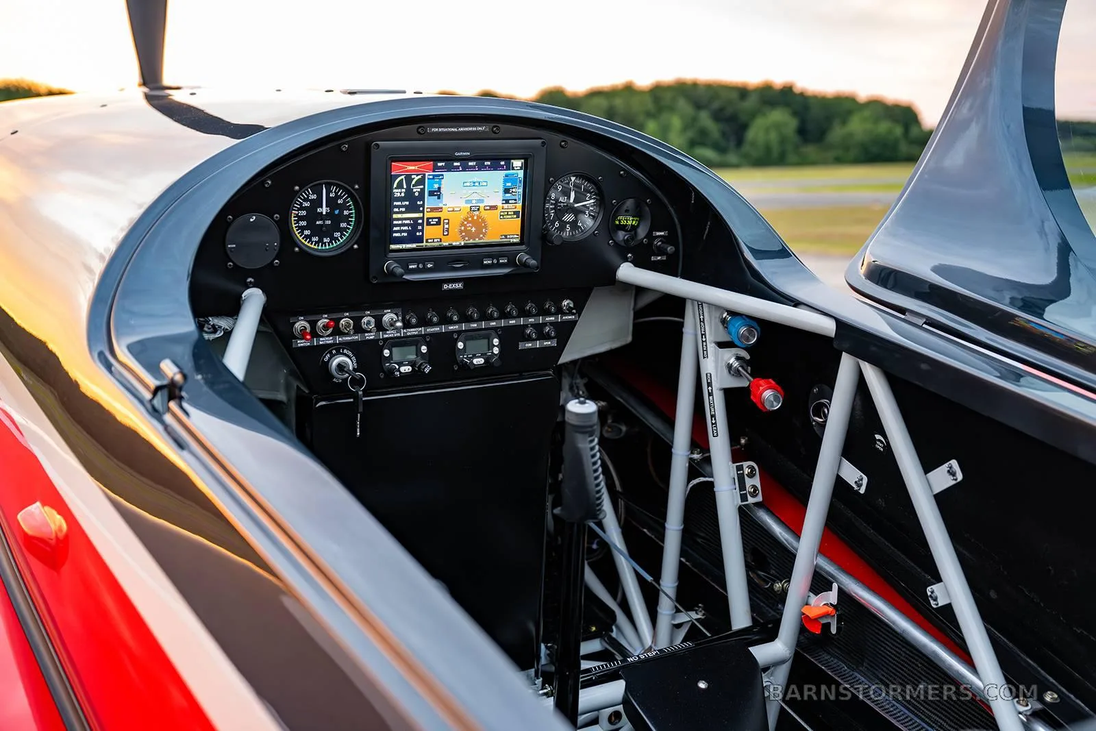 The cockpit of an Extra 330SC aircraft, showing the instrument panel with a large digital display and control stick.