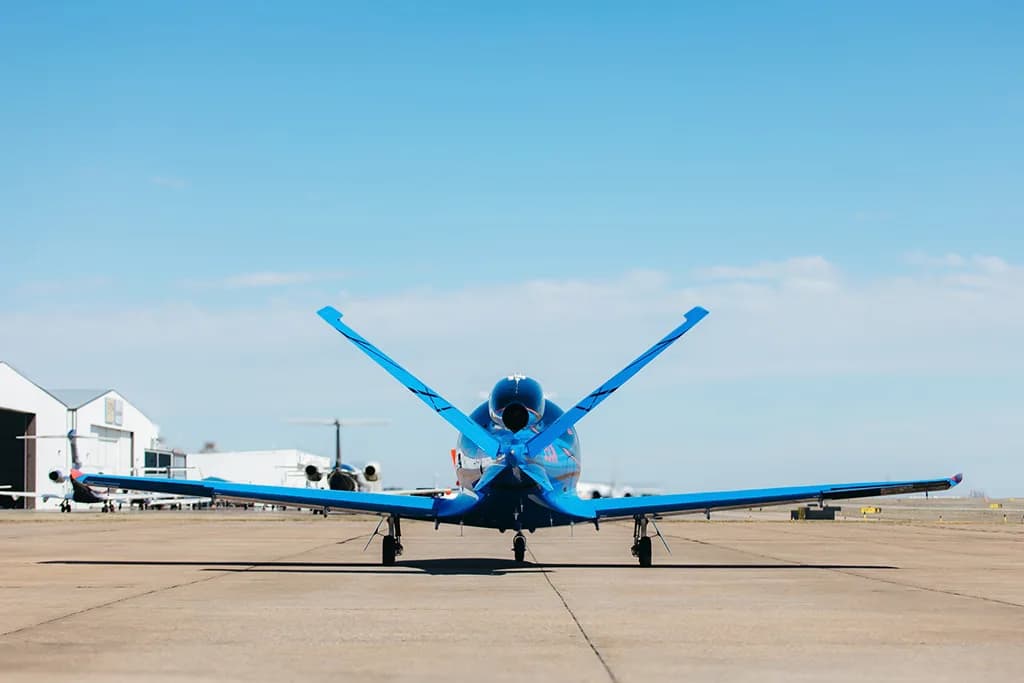 A rear view of a black and blue Cirrus Vision Jet (SF50) with its V-tail on an airfield.