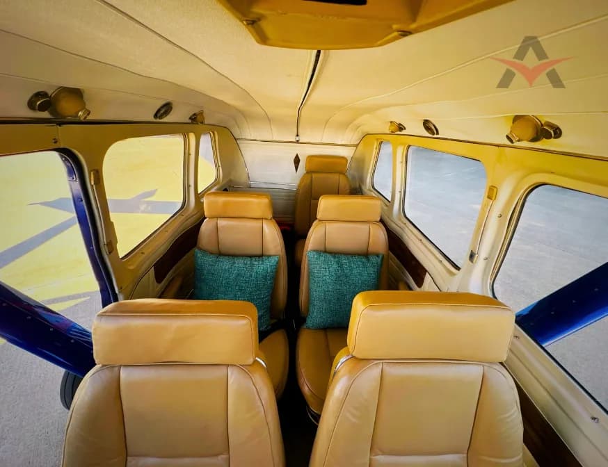 Interior of an aircraft with tan leather seats and green pillows.