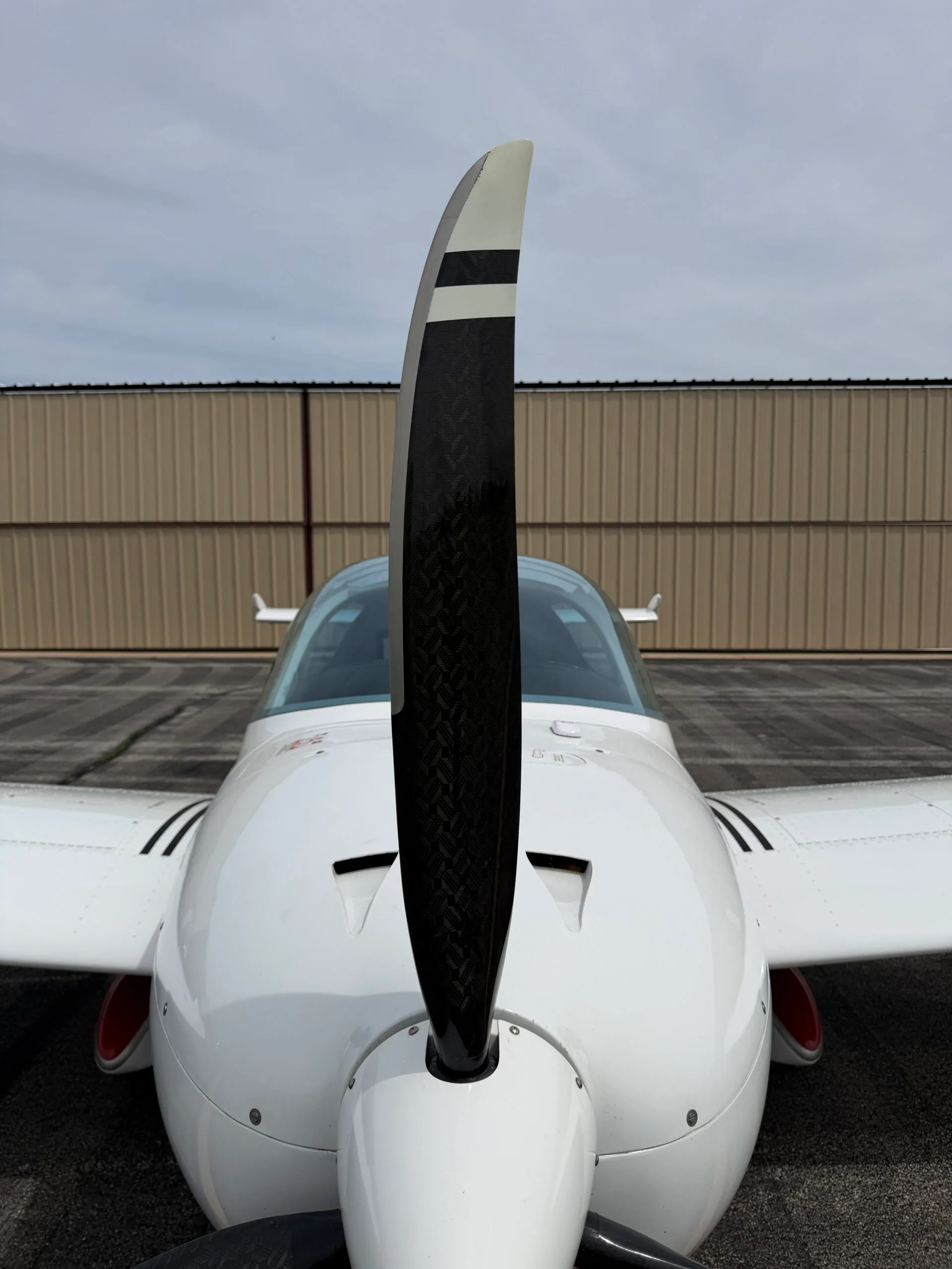 A head-on close-up view of the propeller and nose of the white and red SportCruiser aircraft.