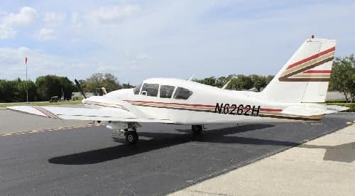 A Piper PA-28-181 Archer II with a white and brown stripe paint scheme is parked on the tarmac.
