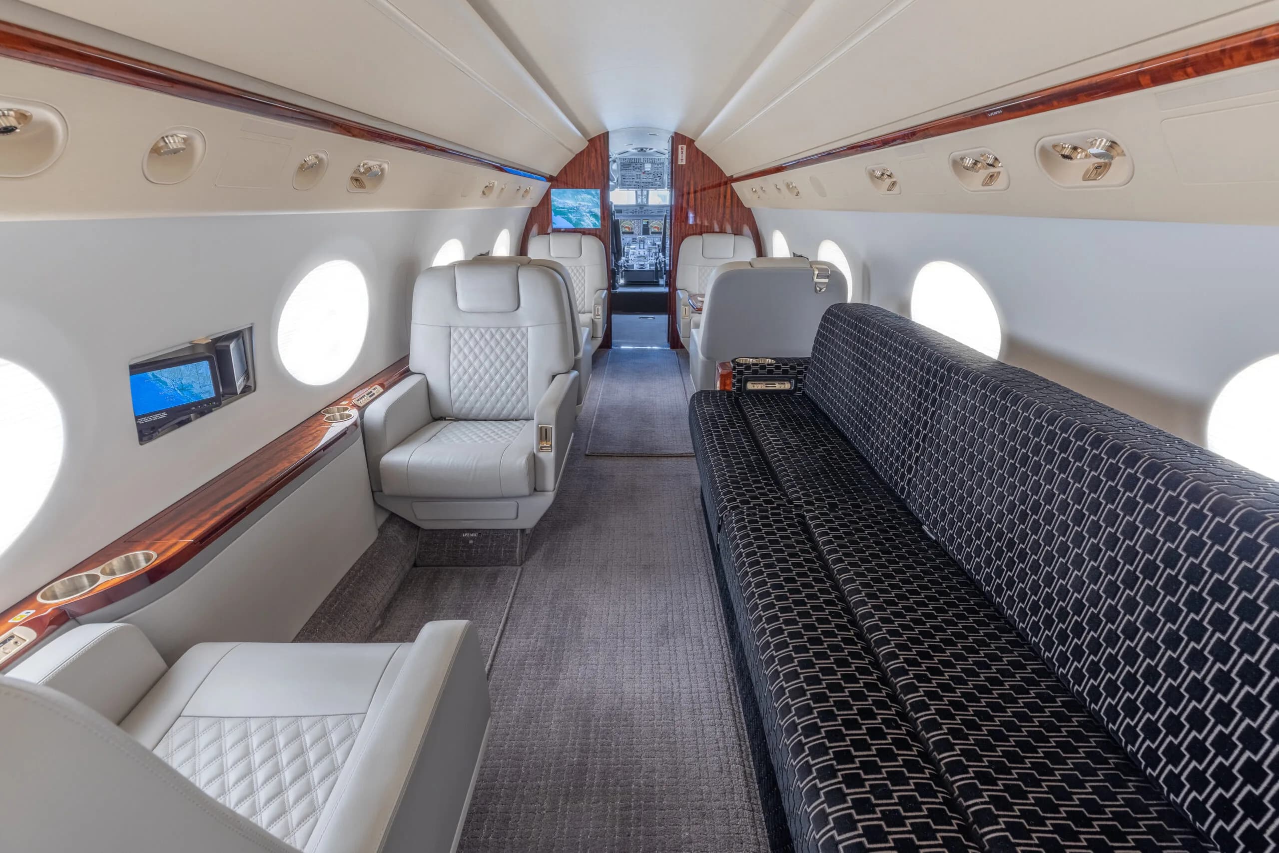 View of the aircraft interior with white leather seats and a patterned sofa.