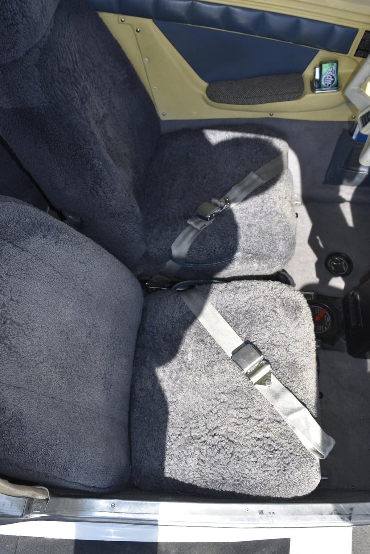 Close-up of the aircraft's seats with sheepskin covers and seatbelts.