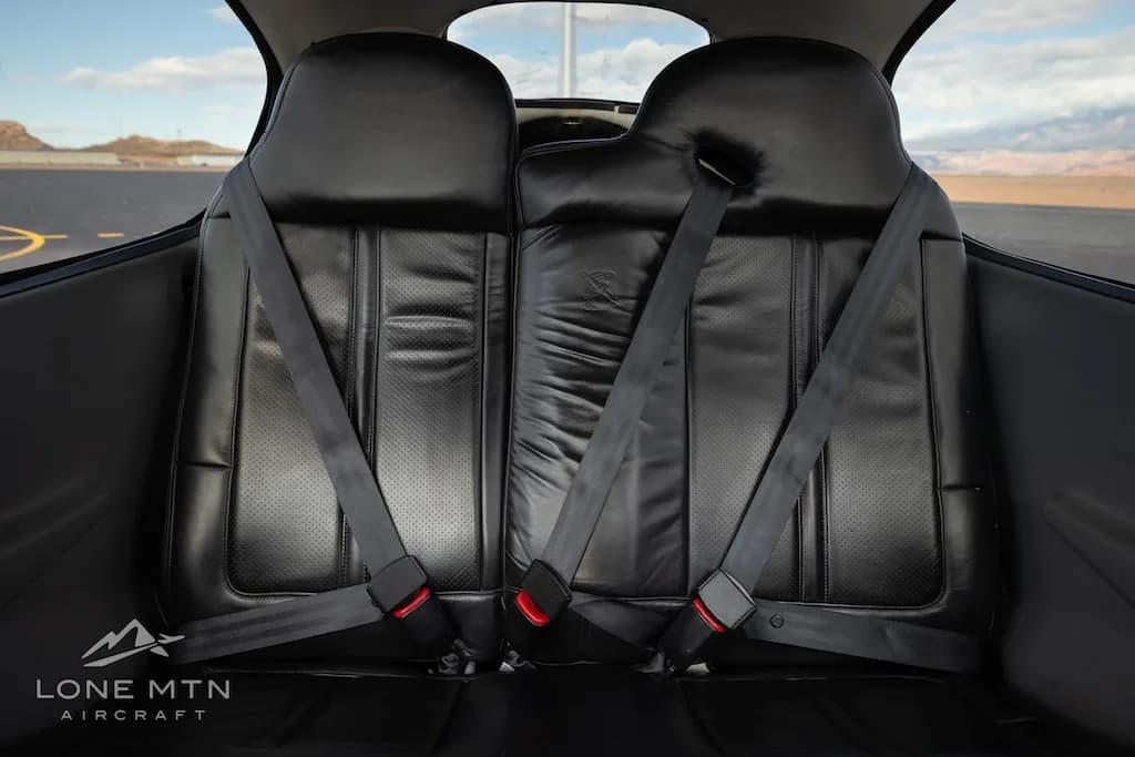 The black leather rear seats of a Cirrus SR22 aircraft cabin, showing seatbelts.