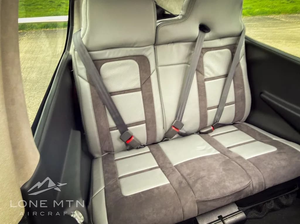 Rear passenger seats of the aircraft, upholstered in two-tone grey fabric with seatbelts.