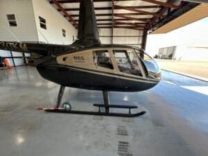 The Robinson R66 helicopter is parked inside a hangar with natural light.