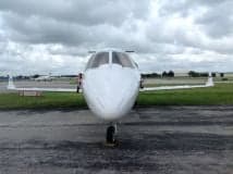 Front view of a white Learjet on the tarmac.