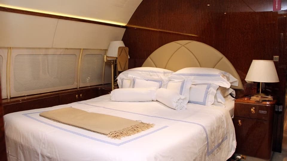 A bedroom inside the aircraft cabin with a comfortable bed and bedside tables.