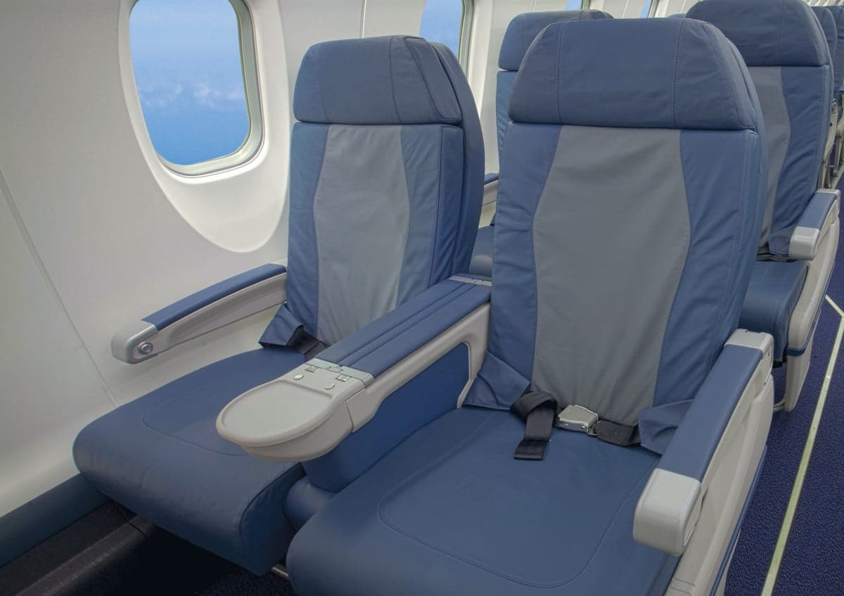 An aircraft cabin interior with rows of blue and gray passenger seats next to a window.