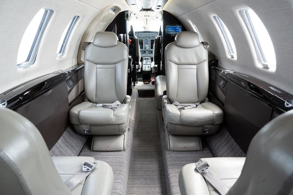View of the aircraft's interior cabin with leather seats facing the cockpit.