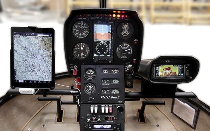 The instrument panel of a Robinson R22 helicopter with a tablet and GPS display.