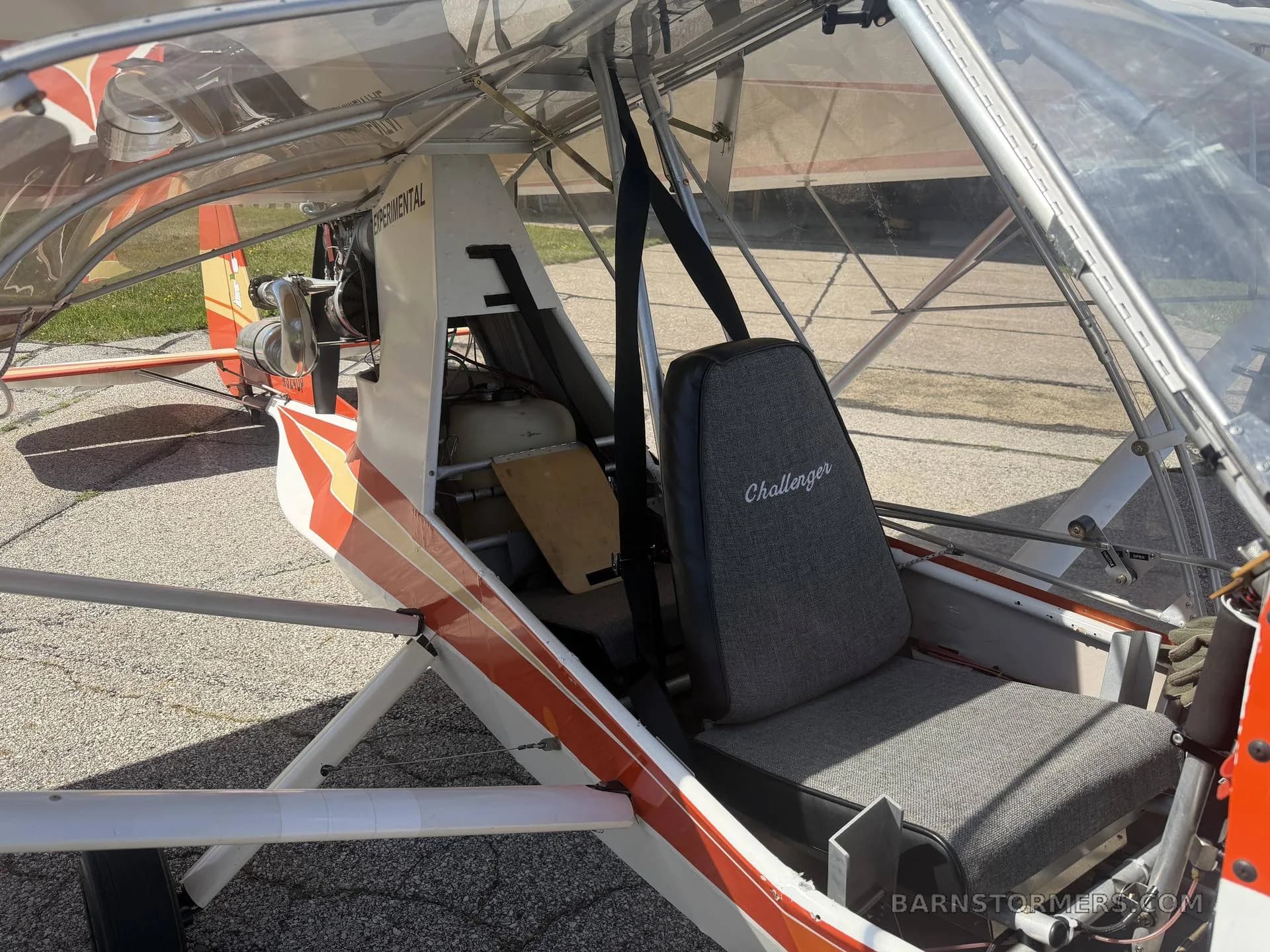 The interior of a single-seat Challenger aircraft, showing the grey fabric seat and exposed frame.