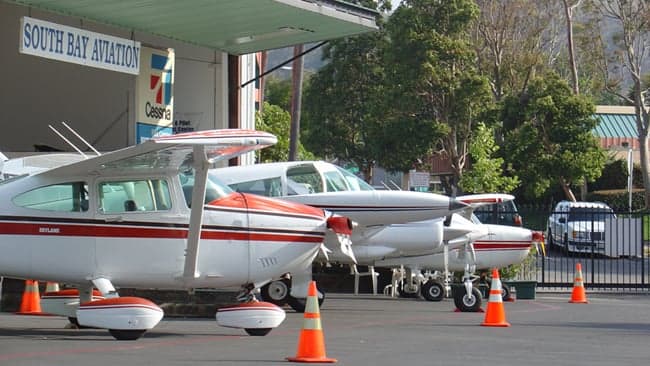 Several light aircraft parked outside South Bay Aviation.