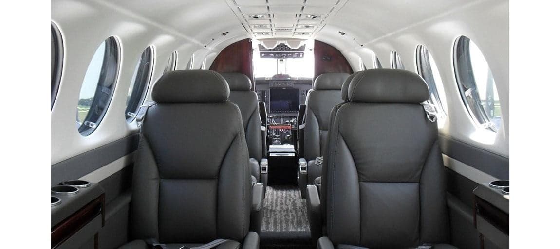The interior of the aircraft features gray leather seats and wood trim.