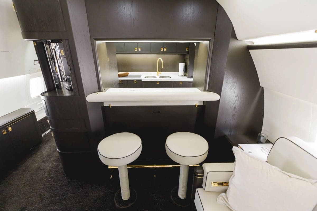 Close-up of the aircraft's bar area with white stools and a dark wood counter.