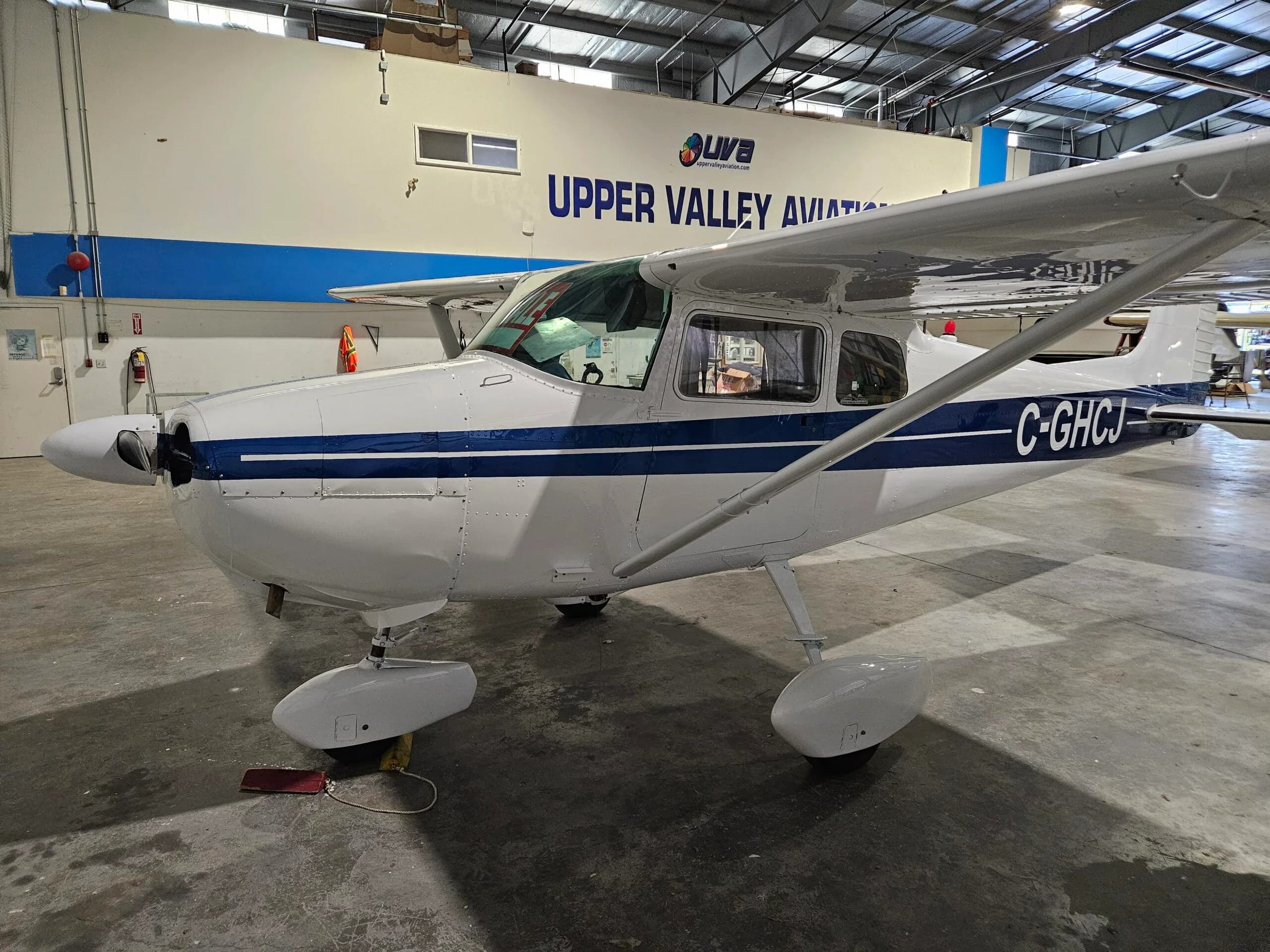 Cessna 172 with blue stripe parked inside a hangar.