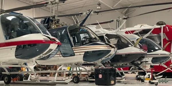 Several MD 500 helicopters are parked in a hangar.