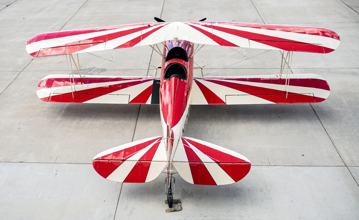 Overhead view of a red and white biplane parked on the tarmac.