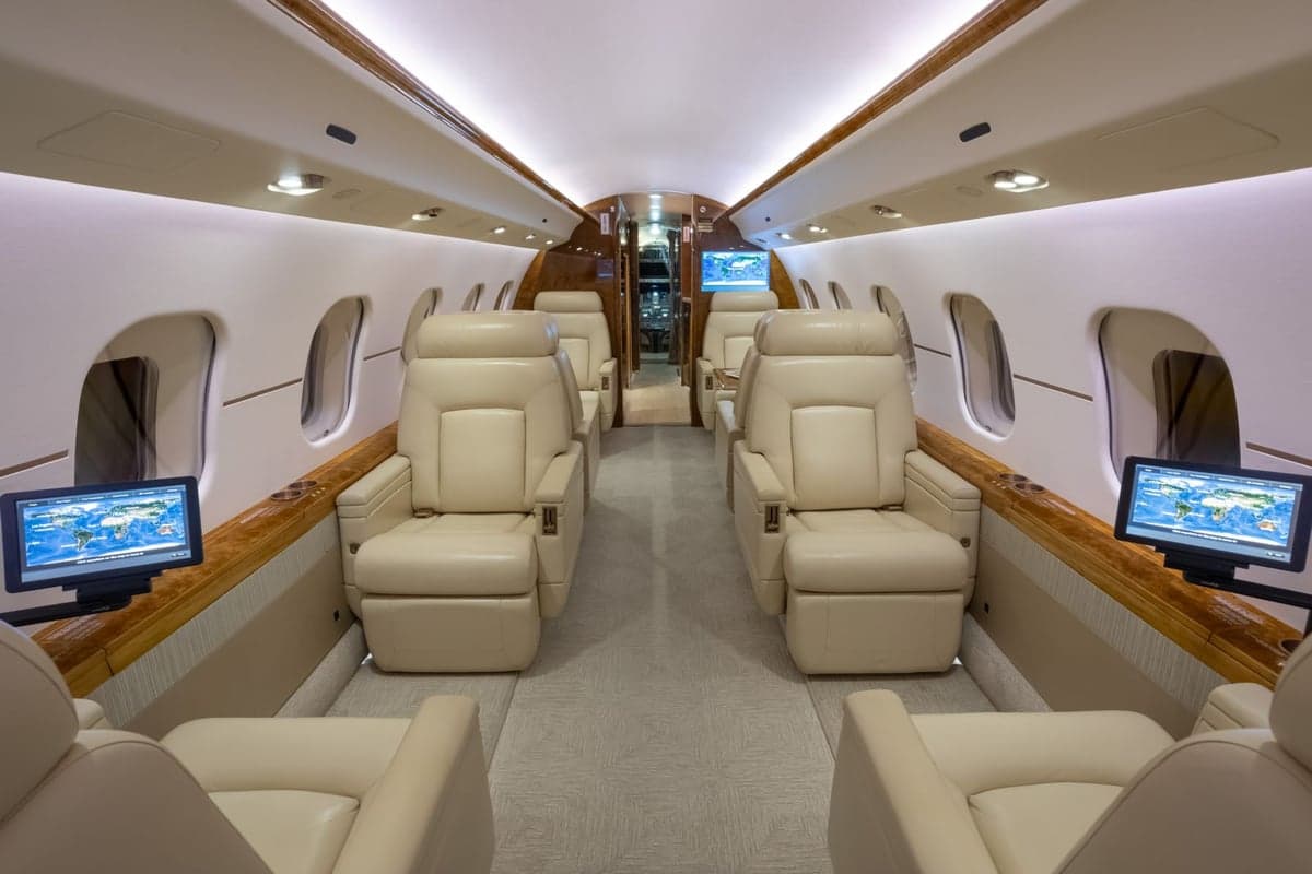 A view of the aircraft's interior with cream-colored leather seats and wood trim.