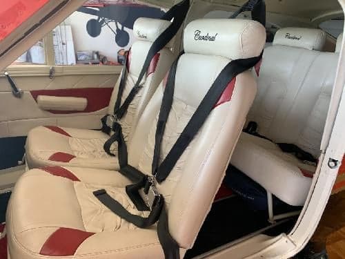 The interior of the aircraft features white leather seats with red accents.