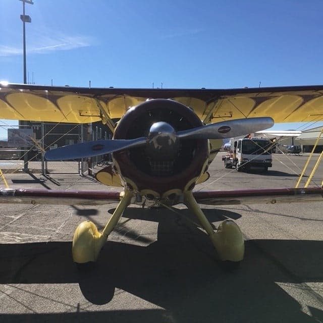 A yellow biplane with red accents parked on the tarmac.