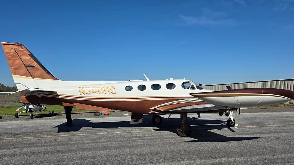 A brown and white Beechcraft King Air is parked on the tarmac.