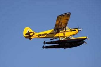 Yellow seaplane flying in the sky.