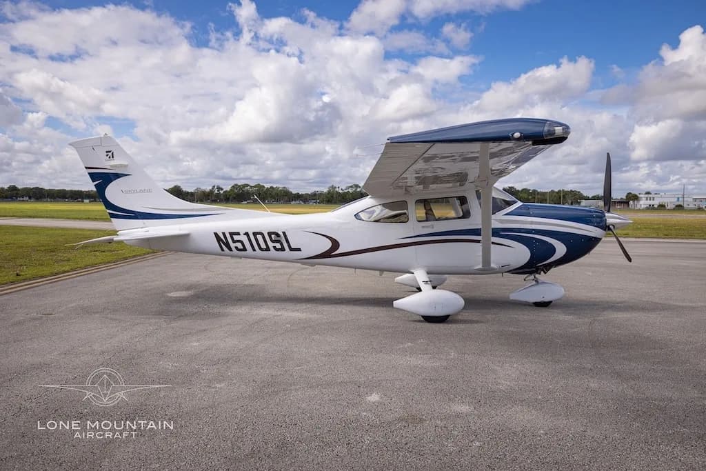 A side view of the white and blue Cessna 182 Skylane aircraft, N510SL, parked on an airfield.