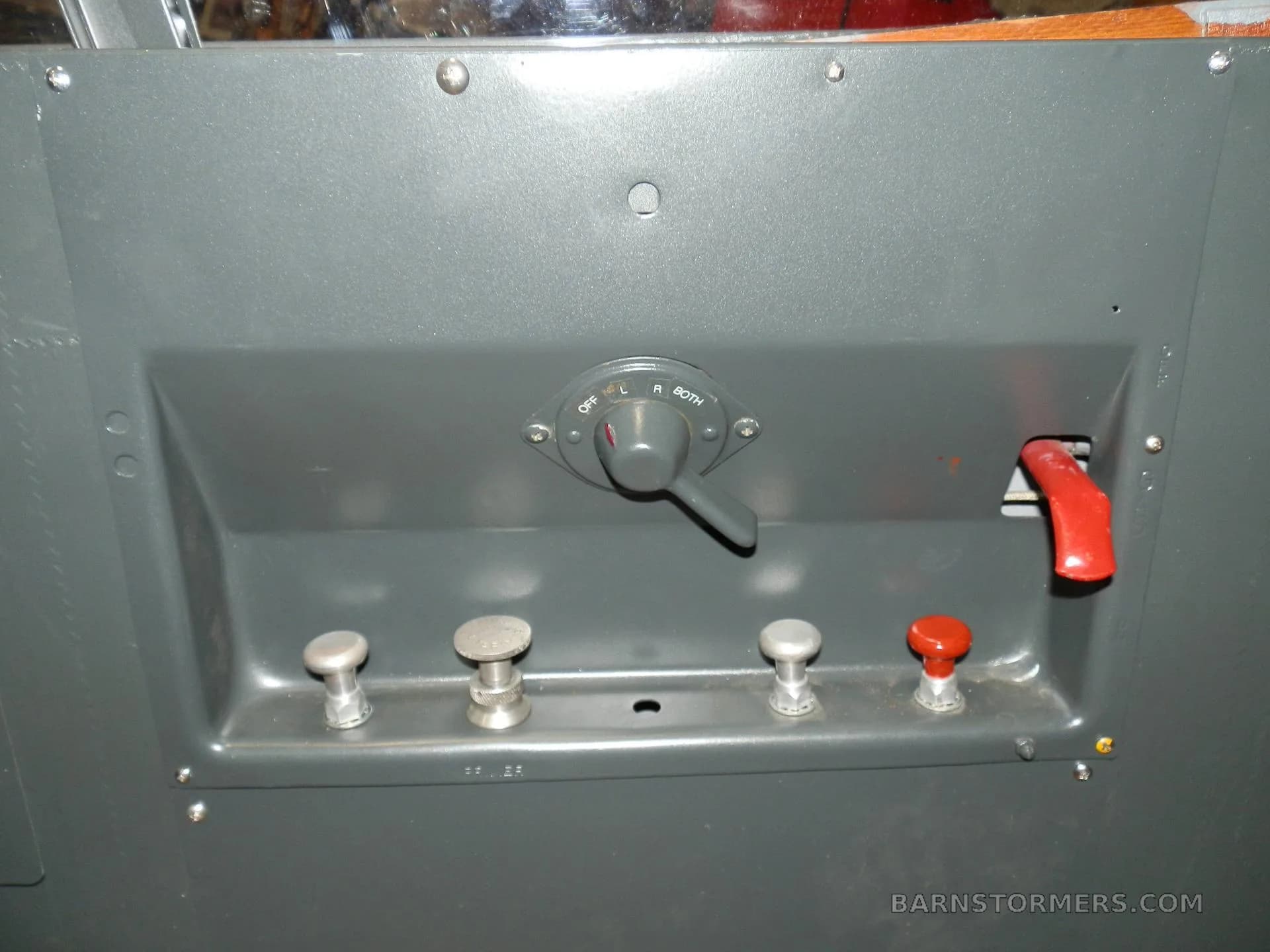 A close-up of a grey aircraft control panel with a fuel selector switch and several push/pull knobs.