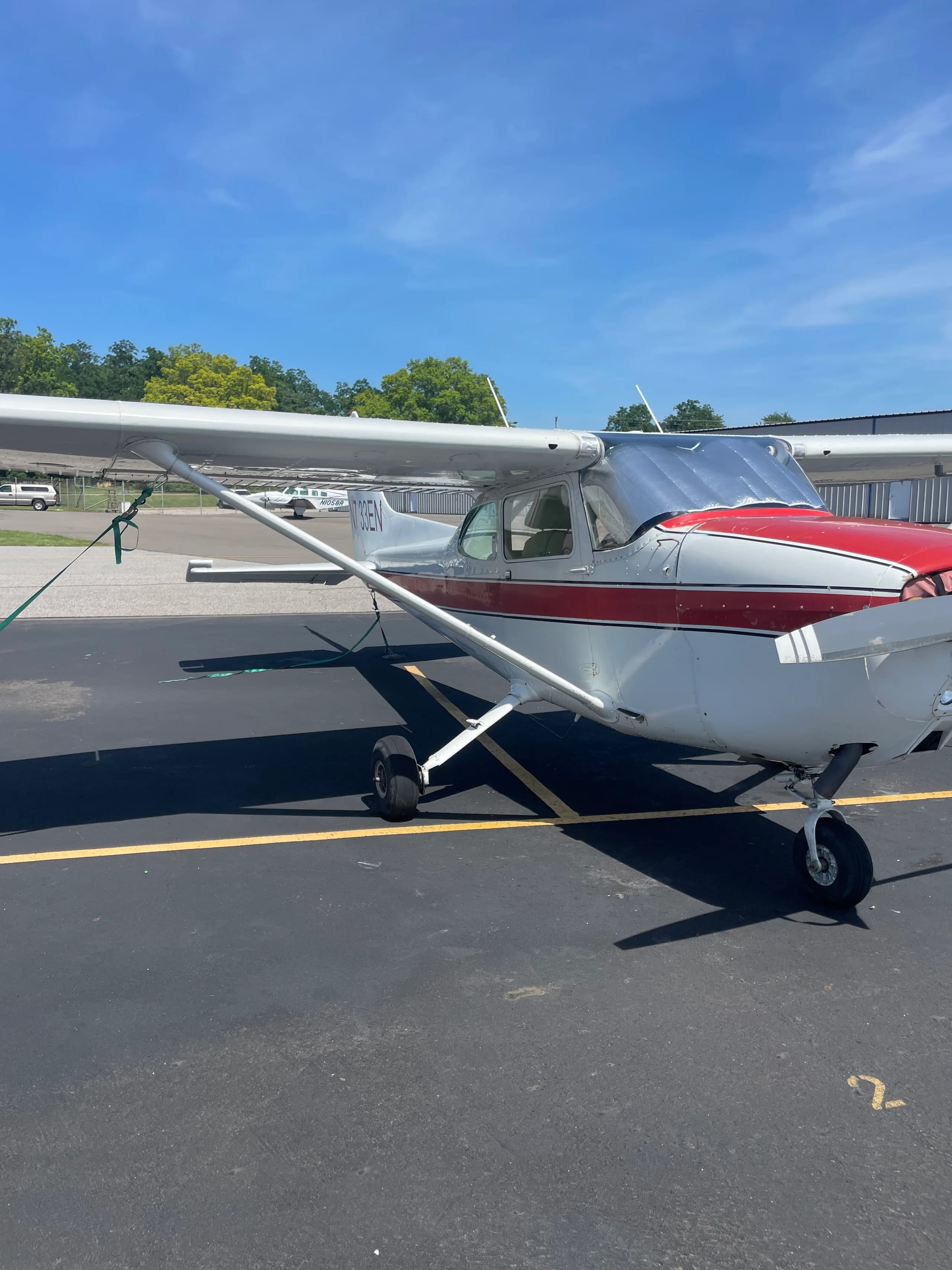 A side view of the white and red Cessna 172, registration N733EN, parked on an asphalt ramp.