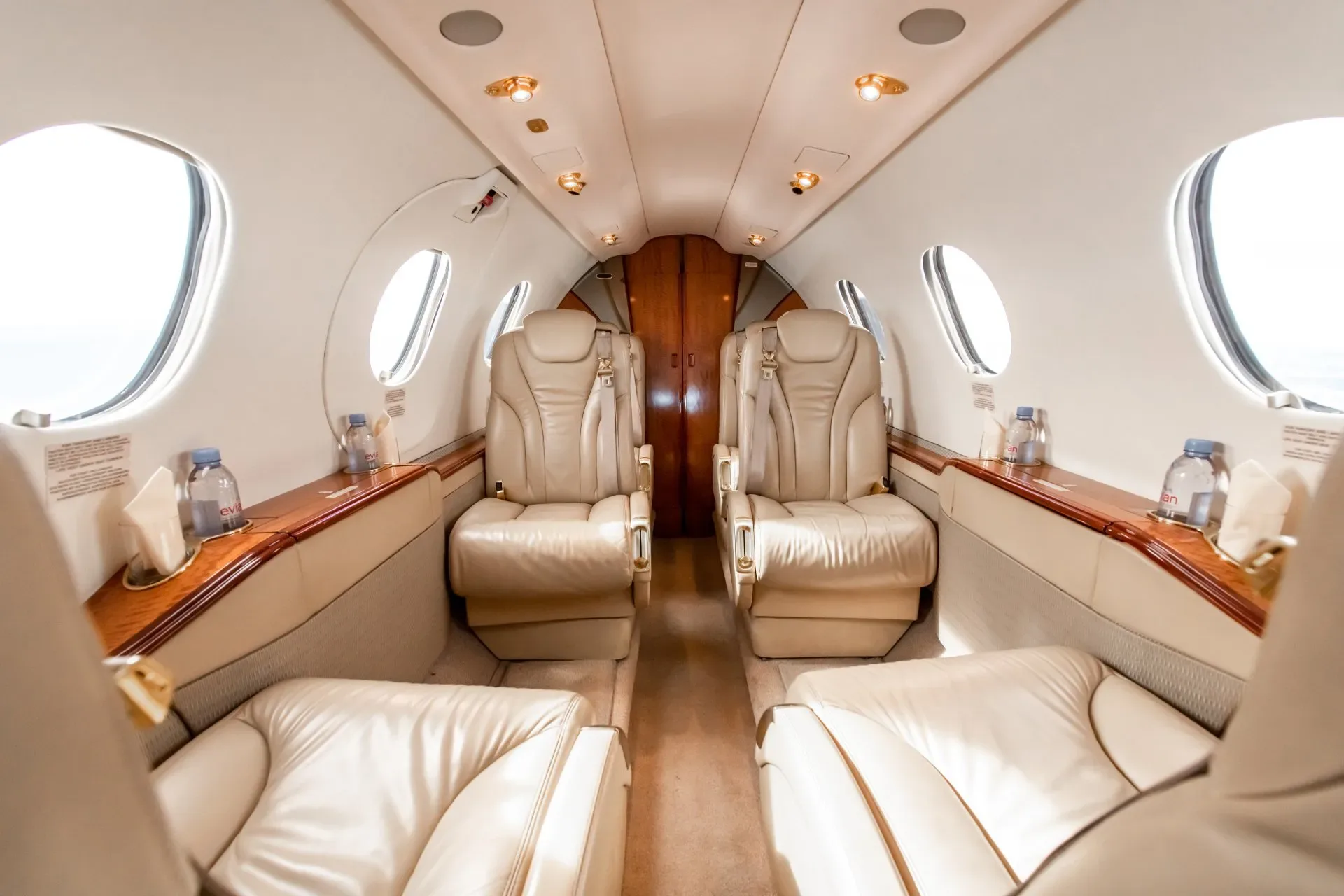 The interior of the jet features cream-colored leather seats and wood trim.